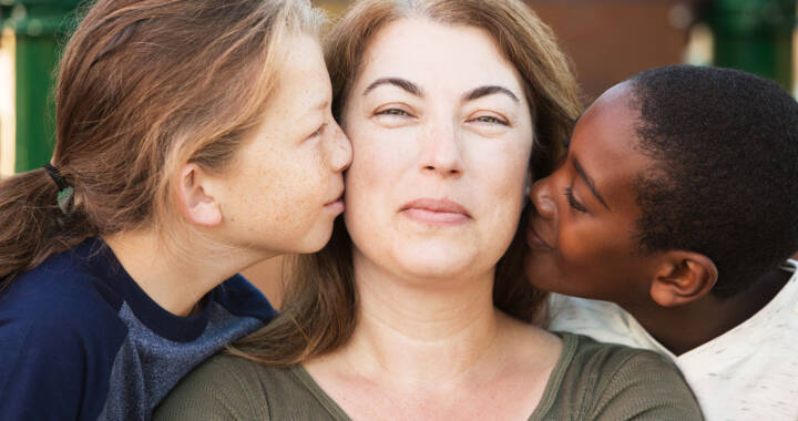 Foster parent getting kissed on the cheek by two of her children