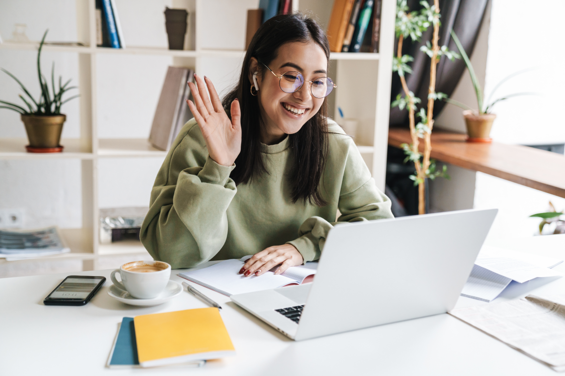 Girl sitting at a computer waving