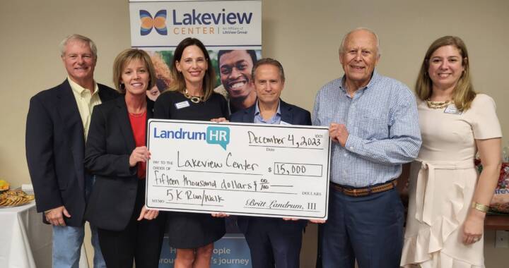 Group of people holding a presentation check at LandrumHR check presentation
