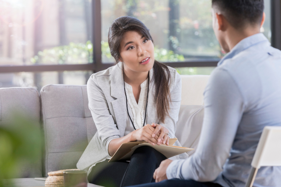 Professional woman sitting and providing guidance to adult man